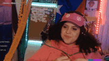 a woman wearing headphones and a pink hat is smiling in front of a sign that says halloween 's