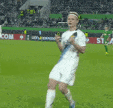 a soccer player is dancing on a field with a uefa conference sign in the background