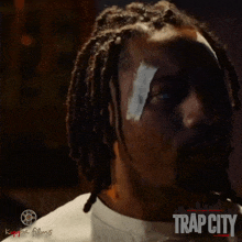 a poster for trap city features a man with a bandage on his eye