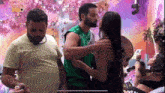 a man in a green vest is hugging a woman in a black dress in a room .