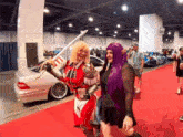 a woman in a purple wig holds a sword next to another woman in a red costume