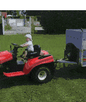 a child is driving a lawn mower with a trailer attached to it