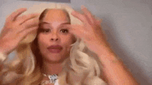 a woman with blonde hair is making a funny face and giving the middle finger .