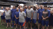 a group of men standing in front of a stadium with one wearing a shirt that says ' mets ' on it