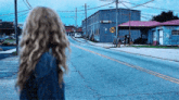 a woman is walking down a street with a train crossing sign on the side of the road .