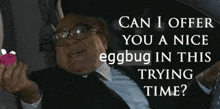 a man in a suit and tie is holding an egg and asking if he can offer a nice eggbug in this trying time ..