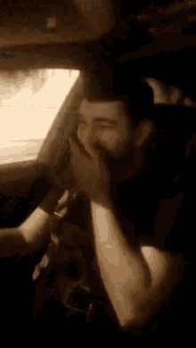 a man with a beard is sitting in a car with his mouth taped to the window .