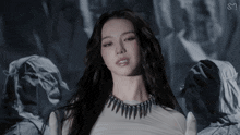 a woman wearing a white top and a black necklace with the letter s on it