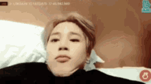 a young man is making a funny face while laying in bed .