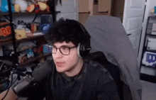 a man wearing headphones and glasses is sitting in front of a microphone .