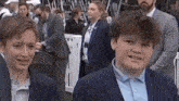 two young boys in suits are standing next to each other in a crowd .