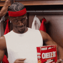 a man is holding a box of cheez-it