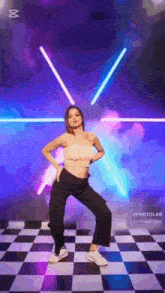 a woman is dancing on a checkered floor in front of a neon light .