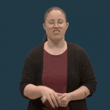 a woman wearing glasses making a funny face with her hand