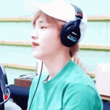 a man wearing headphones and a baseball cap is sitting in front of a computer .