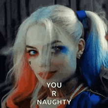a woman in a harley quinn costume is smiling and saying `` you 're naughty '' .