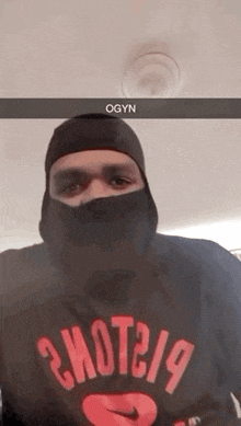a man wearing a black mask and a red t-shirt is taking a selfie .