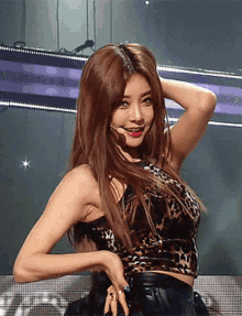 a woman in a leopard print crop top is dancing on a stage