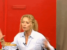 a woman in a white shirt is sitting in front of a red wall with the word star on it .