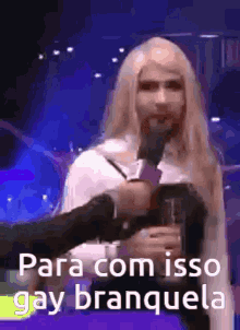 a woman with long blonde hair is holding a glass and says para com isso gay branquela .