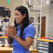 a woman wearing a blue shirt is clapping her hands