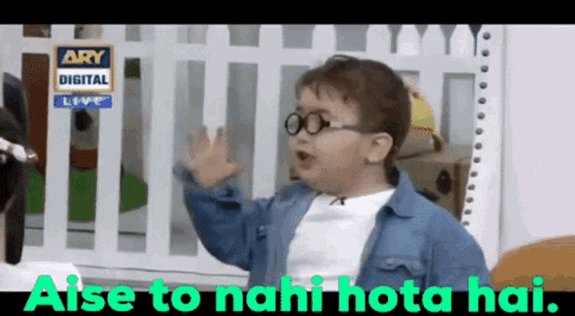 a little boy wearing glasses is standing in front of a white fence and says 