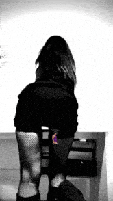 a woman in a black skirt and fishnet stockings stands on a table