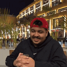 a man wearing a red hat and a black nike hoodie looks at his phone
