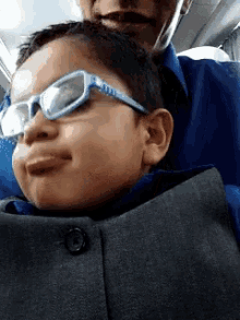a young boy wearing glasses is sitting on a man 's lap