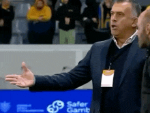 a man in a suit is talking to another man in front of a sign that says safer gamb