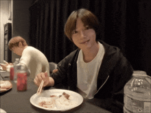 a man is sitting at a table with a plate of food and chopsticks