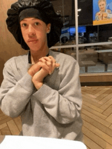 a young man wearing a gray sweatshirt and a black hat