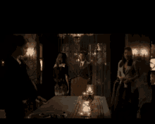 a group of people are standing around a table with candles