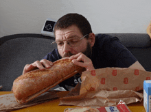 a man is eating a loaf of bread from a bag that says ' bakery ' on it