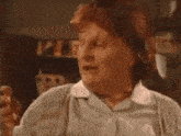 an elderly woman with red hair is making a funny face while standing in a kitchen .