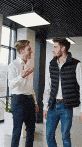 two men are standing next to each other talking