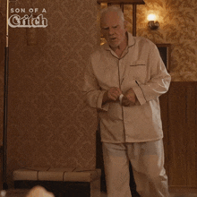 a man in pajamas is standing in front of a wall that says son of a snitch