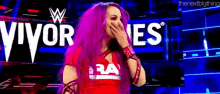 a woman with pink hair is covering her mouth in front of a sign that says " vivor es "