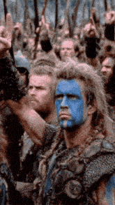 a man with blue paint on his face is standing in front of a crowd