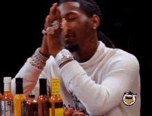 a man sitting at a table with bottles of hot sauce and a sticker that says ' shark ' on it
