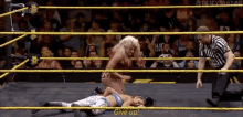 a woman is laying on the ground in a wrestling ring while a referee looks on
