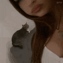 a woman with a cat on her shoulder and the word ora on the bottom right