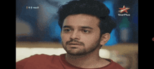 a man with a beard is sitting in front of a starplus sign