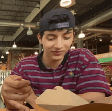 a man wearing a striped shirt and a baseball cap is looking at something