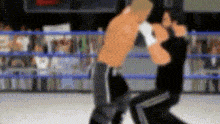 two men are boxing in a ring with a crowd watching .