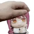 a hand is holding a doll with pink hair and orange eyes .