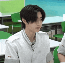 a young man is sitting in a classroom with green chairs .