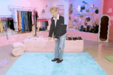a man is standing on a blue rug in front of a wall of clothes