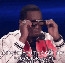 a man is wearing sunglasses while talking into a microphone and says `` if i send you this get the baby oil ready ''