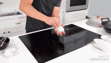 a man is putting a piece of aluminum foil on a stove top that is made in animatica